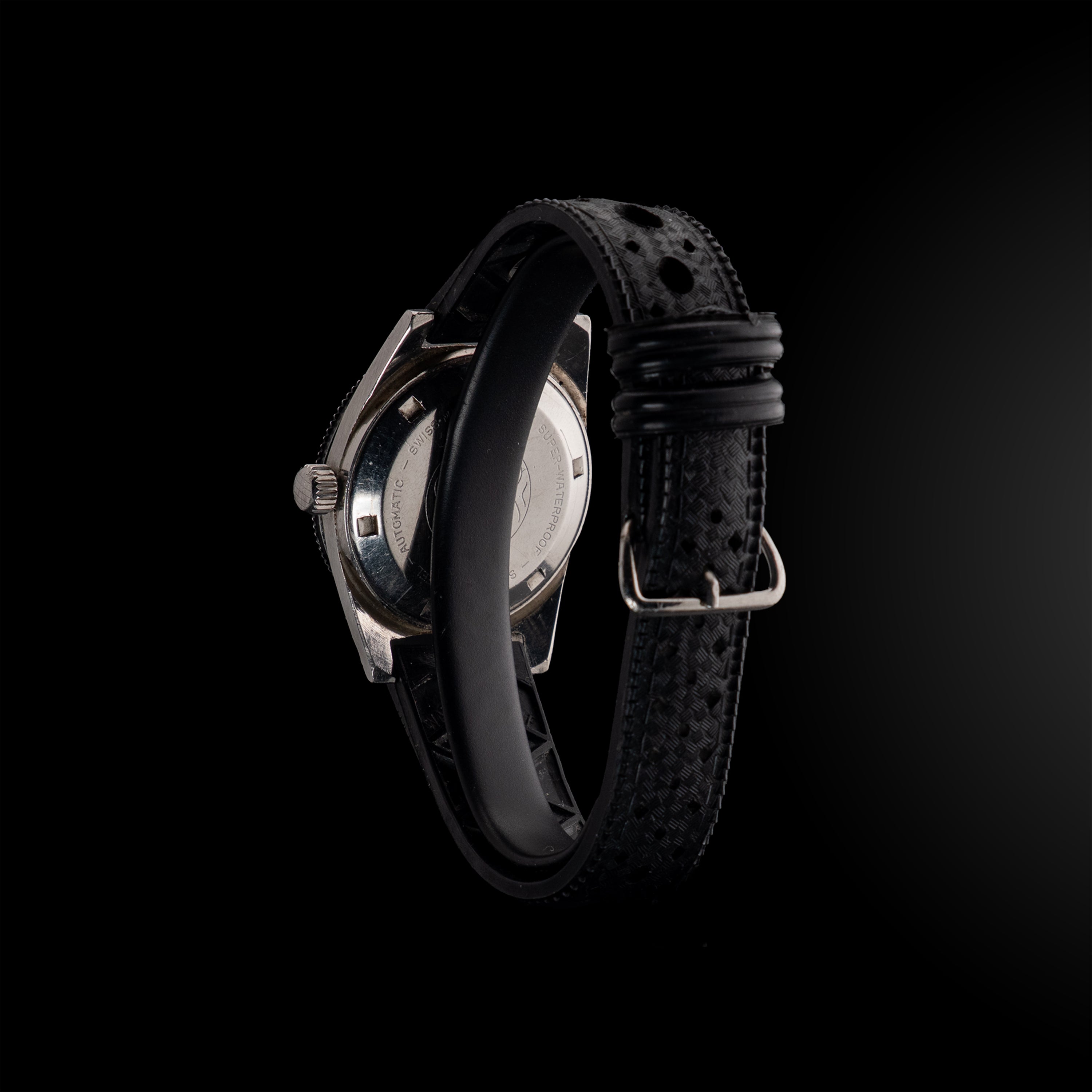 Montre LIP Dauphine vue de dos en angle, dévoilant le fond de boîtier gravé et le bracelet en caoutchouc perforé