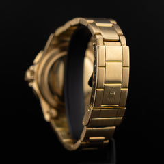 Plan serré sur le fermoir Oyster de la Rolex Submariner or jaune, logo couronne embossé et finitions brossées des maillons