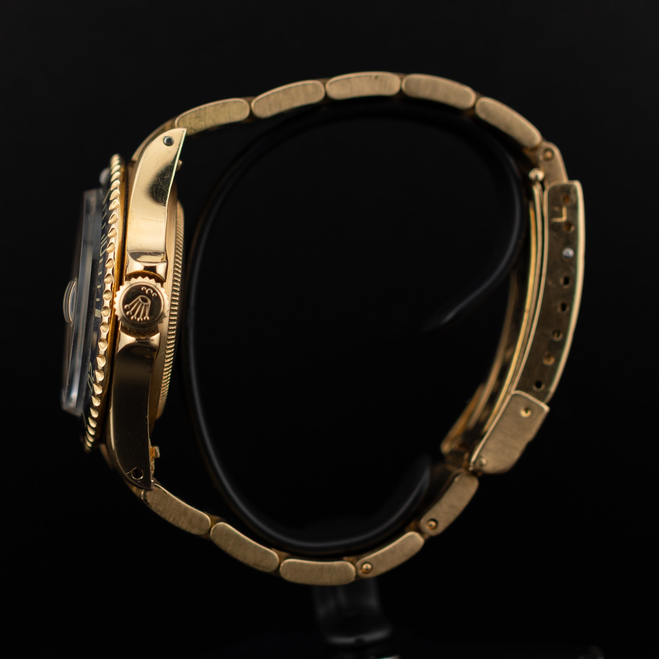 Profil latéral droit de la Rolex Submariner or jaune avec couronne gravée du logo Rolex et bracelet Oyster en arc