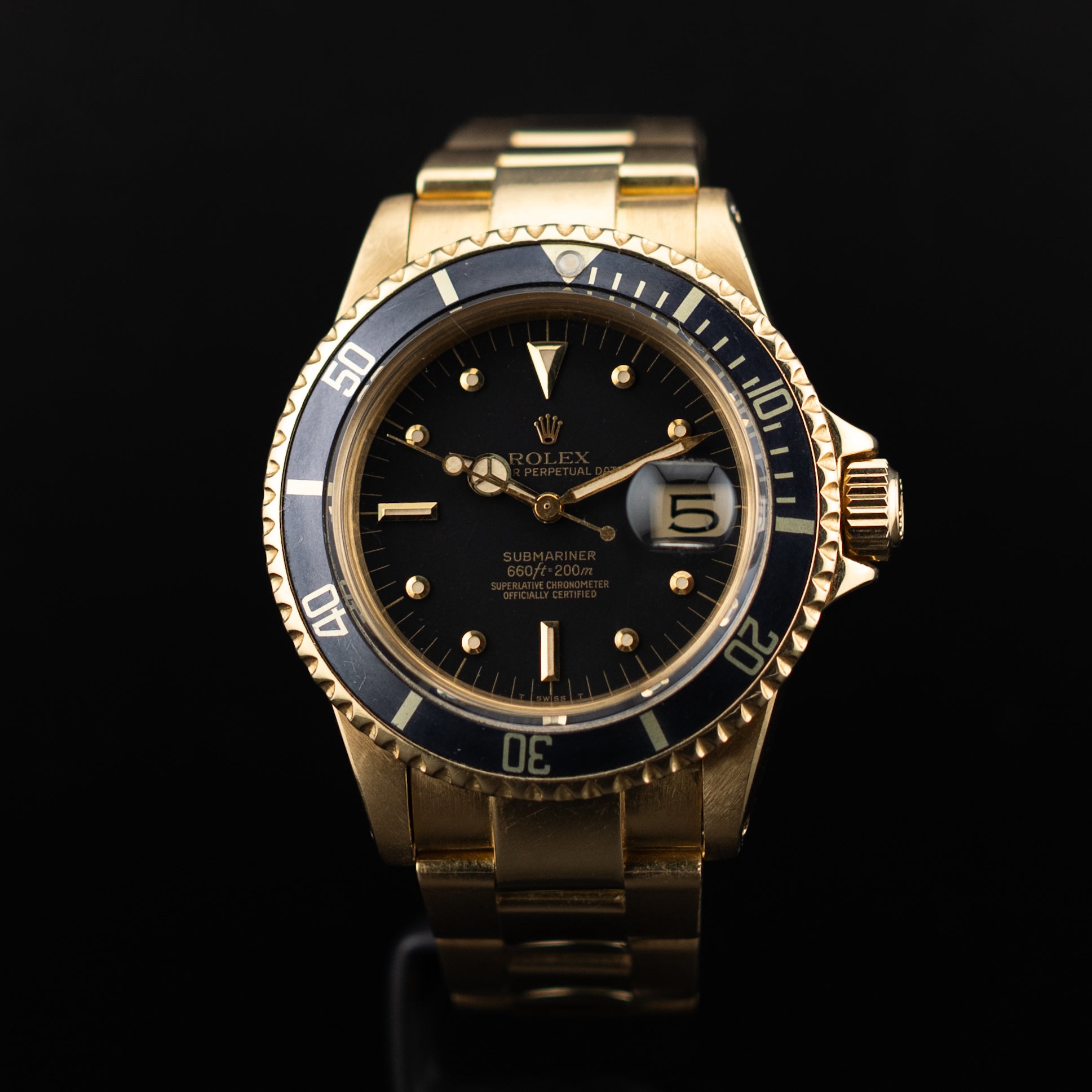 Montre Rolex Submariner en or jaune vue de face, cadran noir à index luminescents, lunette tournante graduée et guichet date cyclope