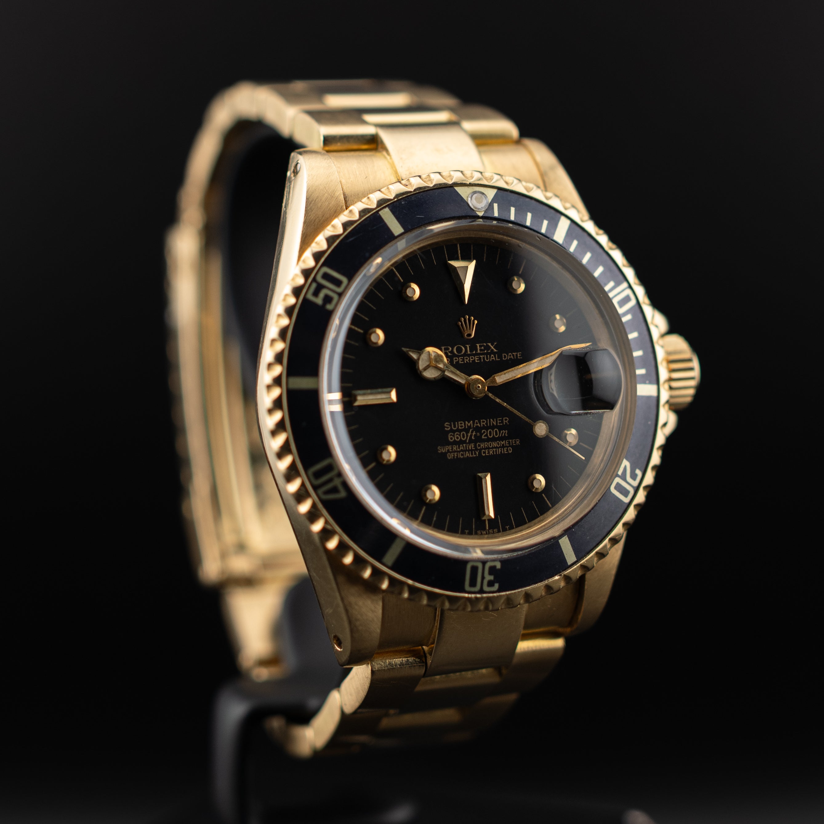 Rolex Submariner or jaune en vue trois-quarts avant gauche, cadran noir, lunette noire crantée et grossissement cyclope du guichet date
