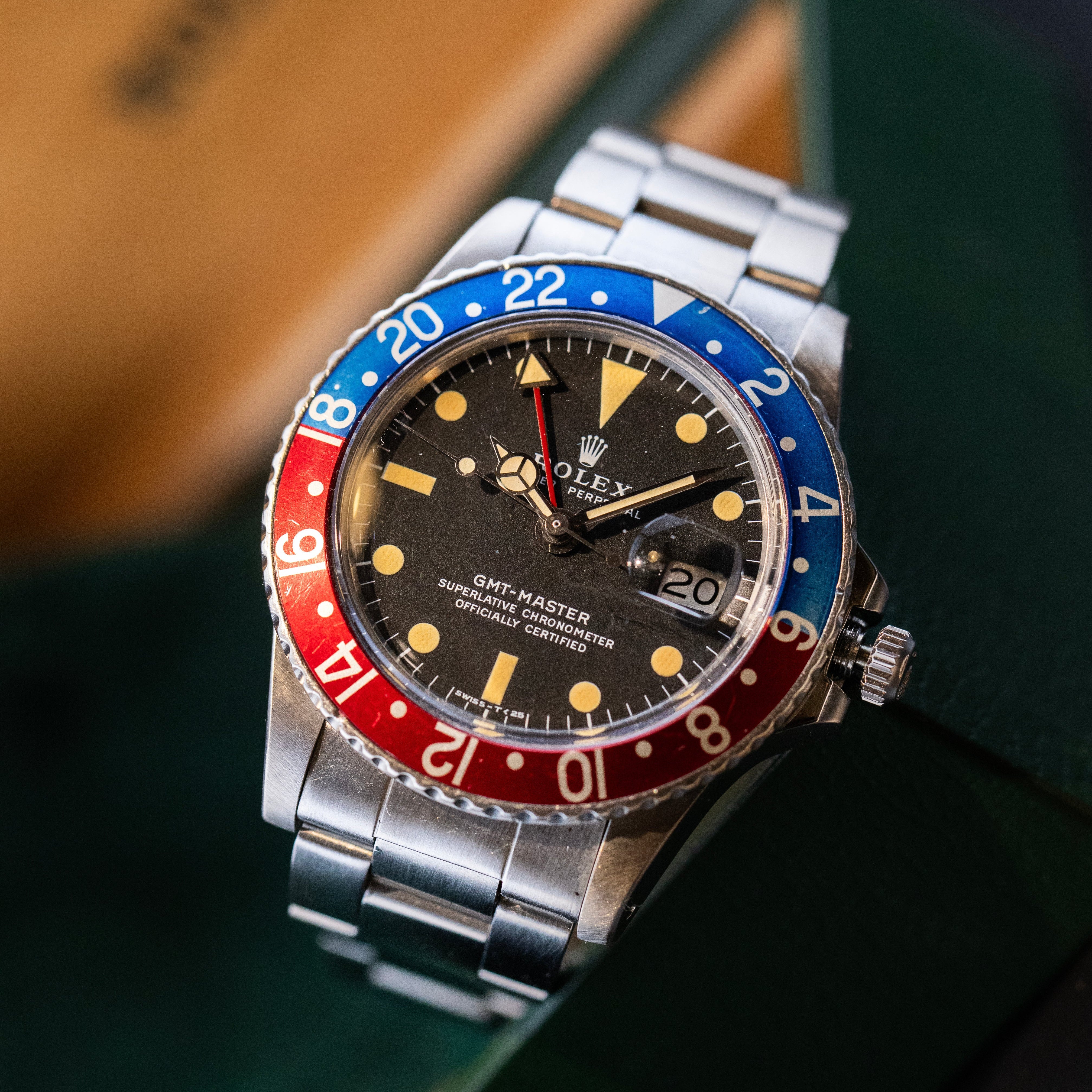Montre Rolex GMT-Master Pepsi vintage cadran noir lunette rouge et bleue sur fond vert